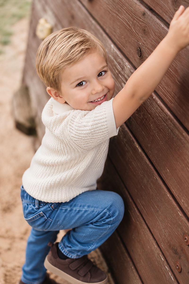 Junge klettert lachend an einem Holzpfosten – Beispielmotiv für Kinderfotos in Artern